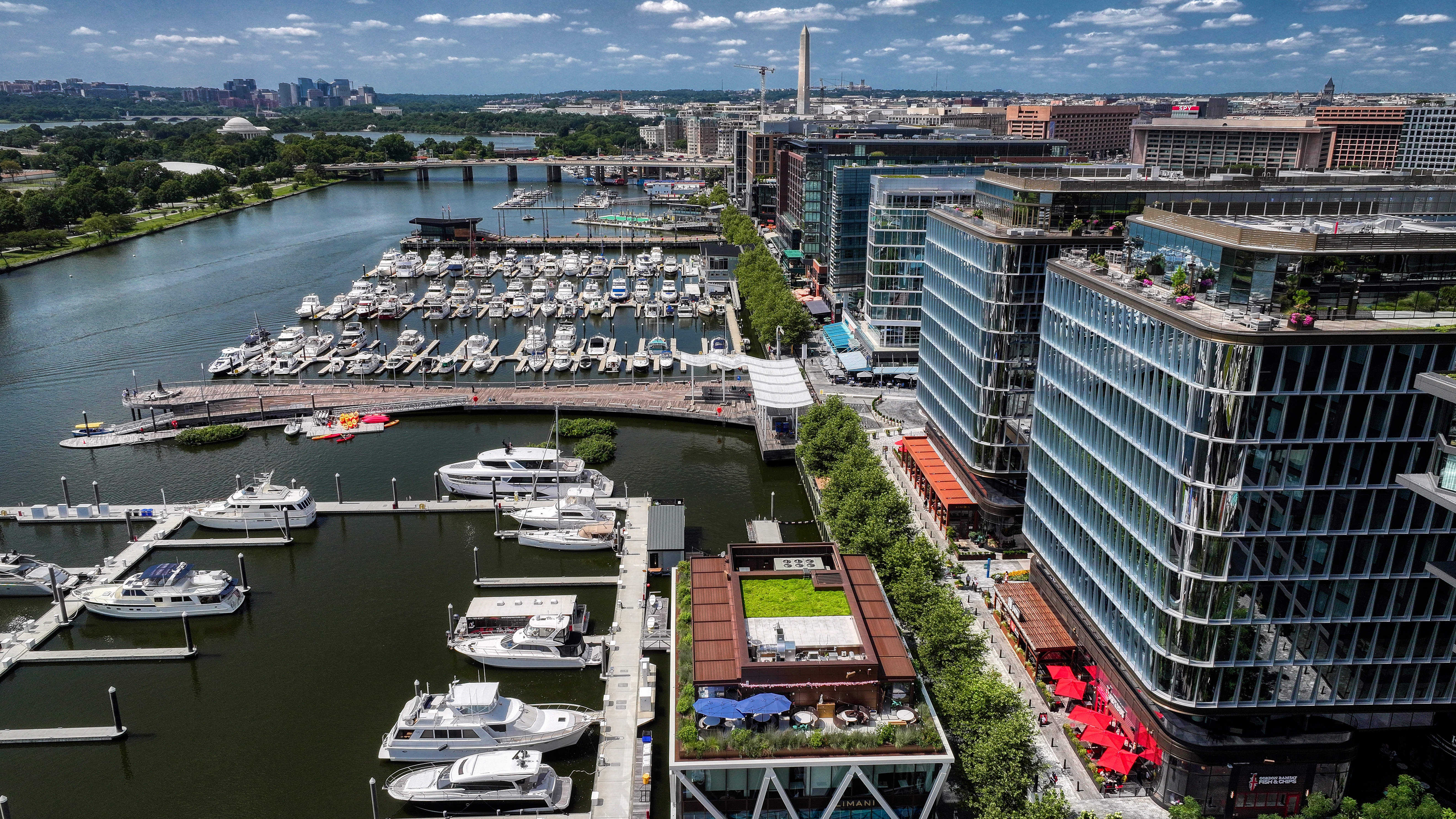 Aerial view of The Wharf marina and waterfront in Washington, DC with the Washington Monument in the distance